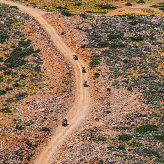 A dirt road winding through a rocky terrain with sparse vegetation. 1