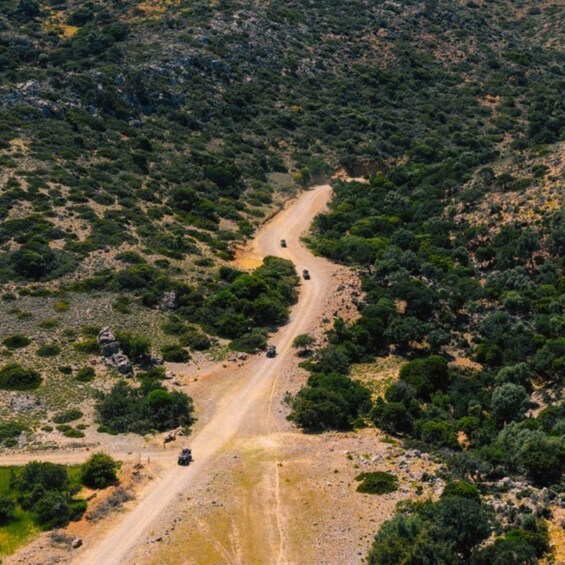 A winding dirt road through a hilly, bush-covered landscape. 4