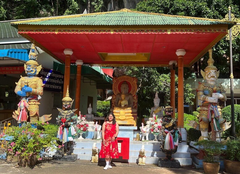 A temple with a central Buddha statue, surrounded by colorful statues and a woman in a red dress. 5