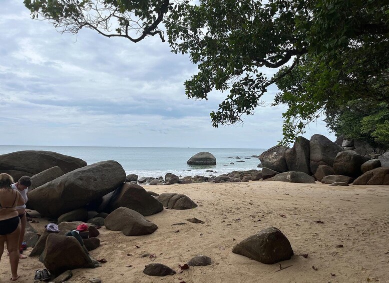 A beach with large rocks and a calm sea under a cloudy sky. 3