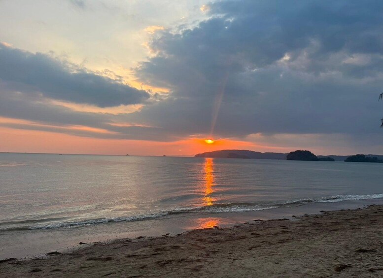 A sunset over a calm sea with a beach in the foreground. 1