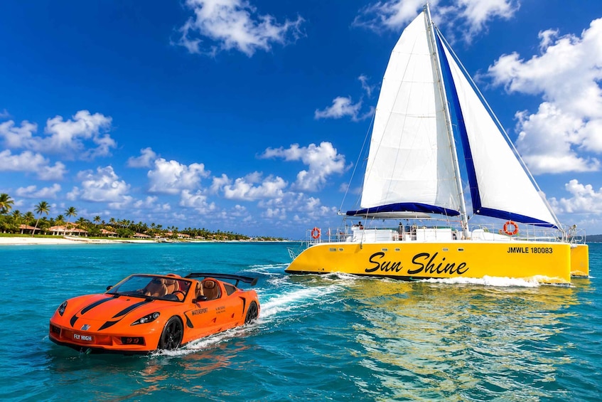 A yellow sailboat named 'Sun Shine' and an orange sports car on the water. 1