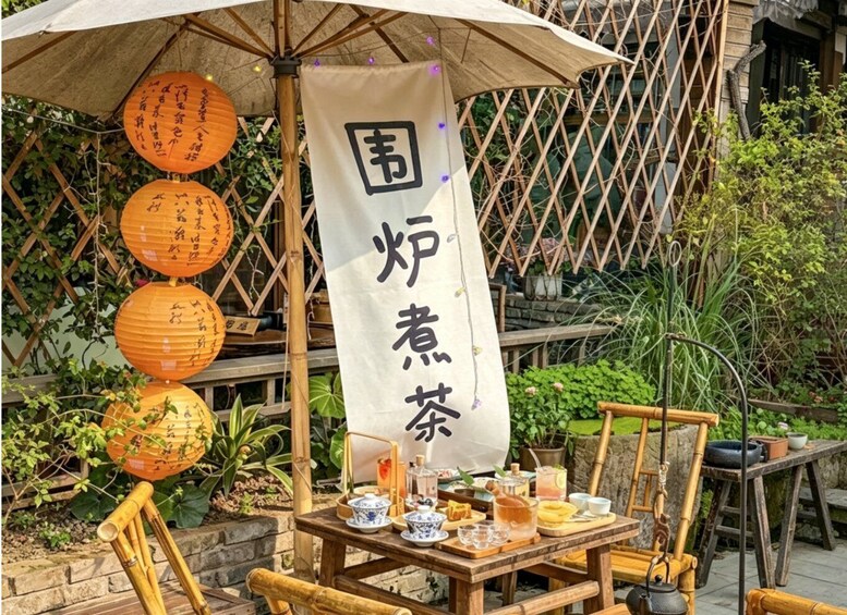 A traditional tea setup with a bamboo umbrella, tea set, and lanterns. 3