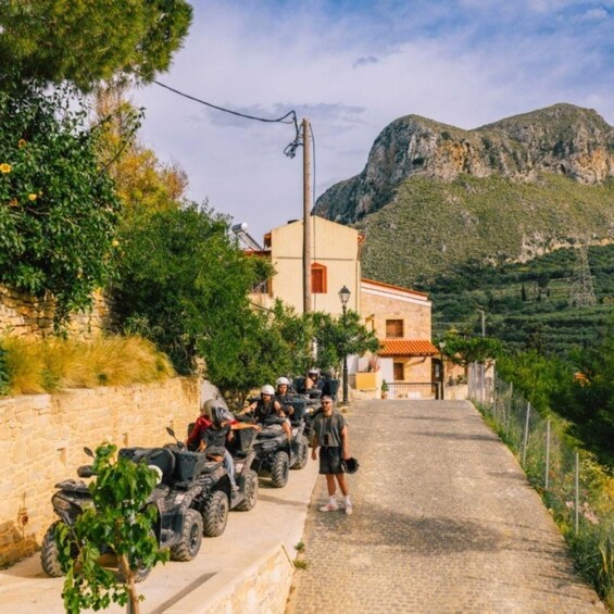 A group of people on ATVs parked on a cobblestone path with a mountain in the background. 1