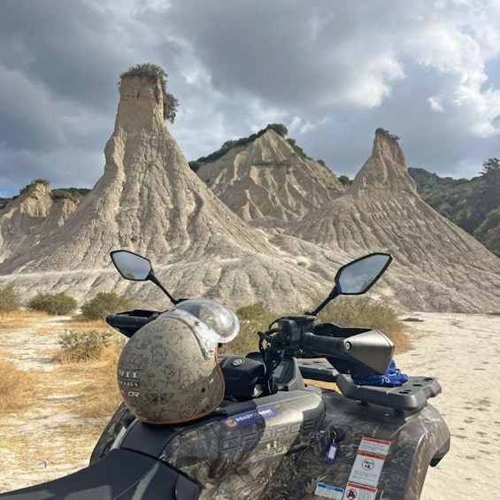 A quad bike with a helmet on it, parked in front of a rocky landscape with two prominent peaks. 3