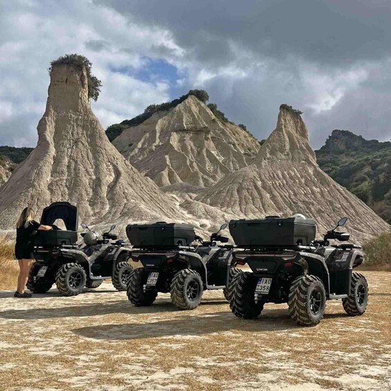 Three quad bikes parked on a dirt path with a rocky mountain landscape in the background. 2