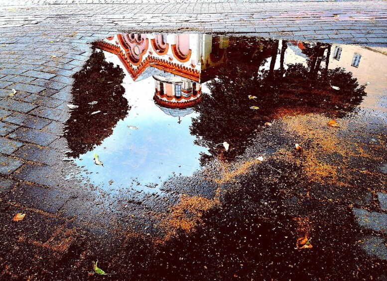 A puddle reflecting a building with a red and white facade. 2