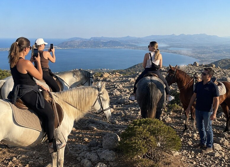 A group of people on horseback overlooking a coastal landscape with mountains in the distance. 2