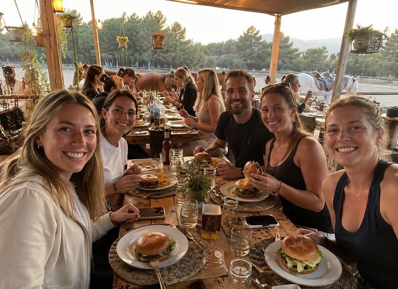 A group of people dining outdoors with horses in the background. 3