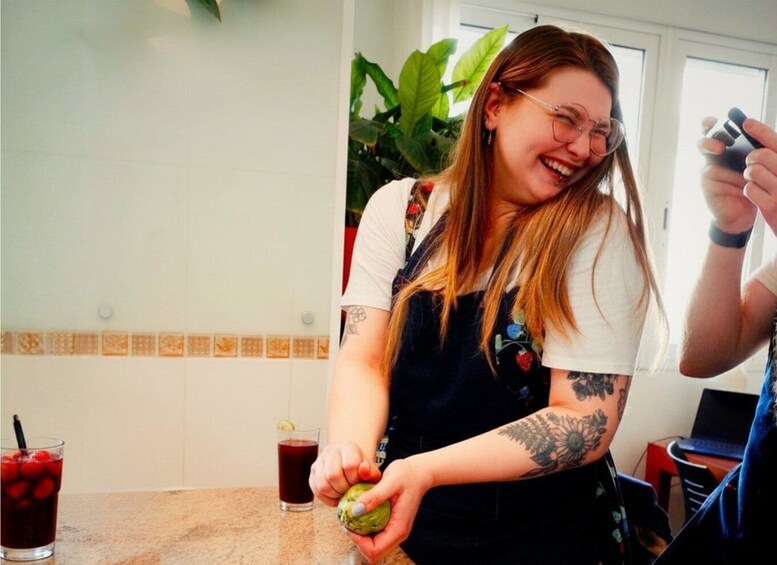 A person squeezing a lime in a kitchen setting with a drink and laptop in the background. 4