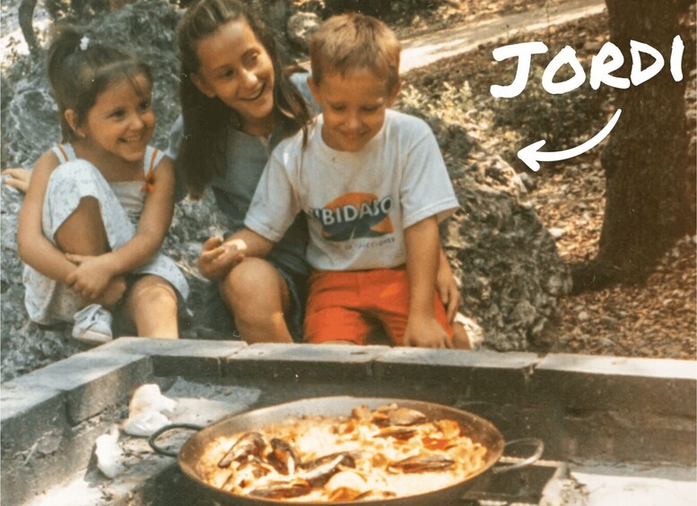 Three people sitting by a fire pit with a pizza on a pan. 5