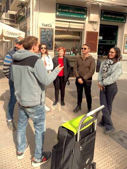 A group of people standing outside a café with a sign that reads 'el café de camilo.' 3