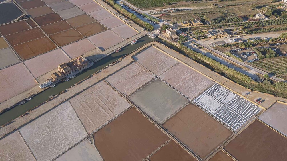 An aerial view of salt pans with a river, buildings, and vegetation. 3