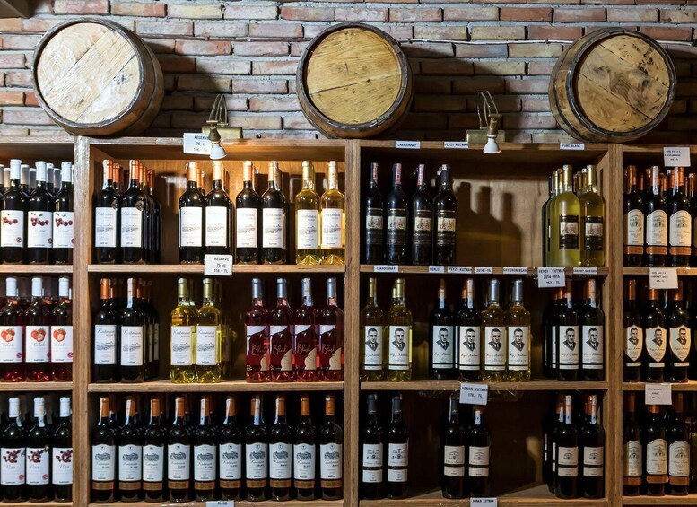 A wine cellar with wooden barrels and shelves of various wine bottles. 4