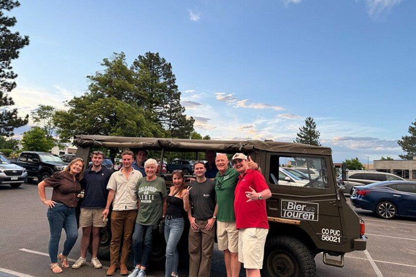 A group of people posing in front of a vehicle labeled 'Bier Touren' with a license plate 'COP 56021' in a parking lot. 3
