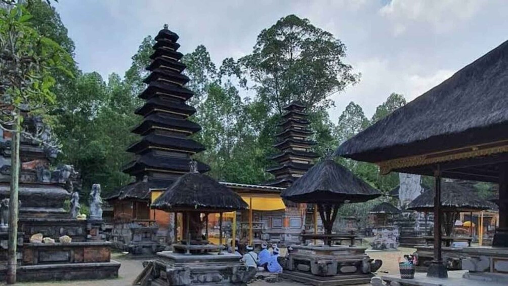 A traditional Balinese temple complex with tiered structures and thatched-roof buildings. 1