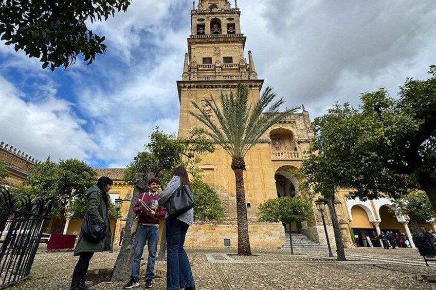 A historic building with a bell tower, palm trees, and a cobblestone courtyard. 4