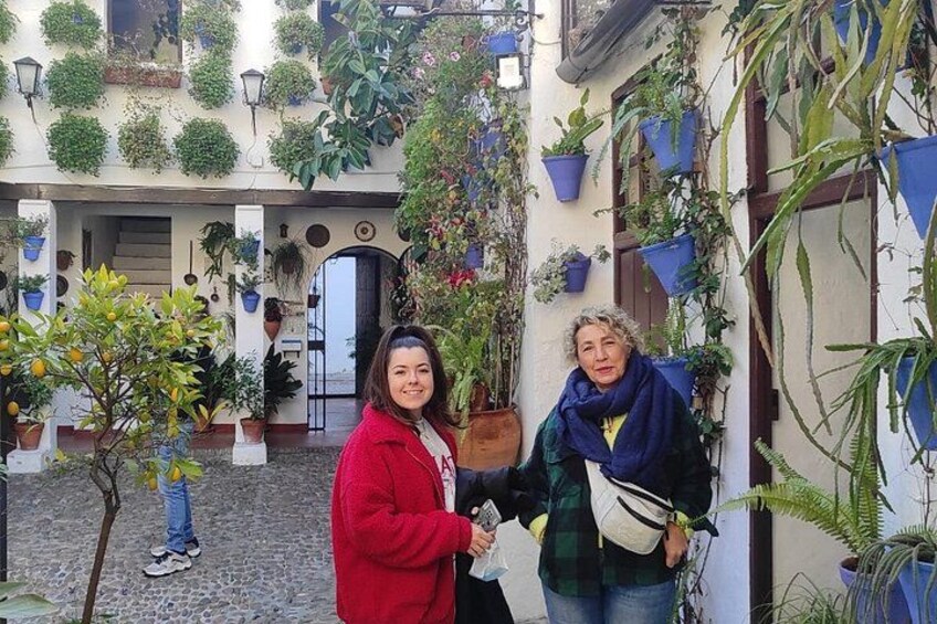 A courtyard with potted plants, a tree, and a building facade. 1