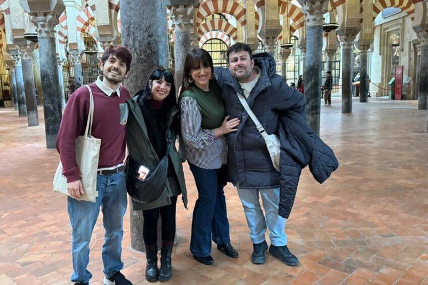 A group of people standing in a historical building with arches and columns. 3