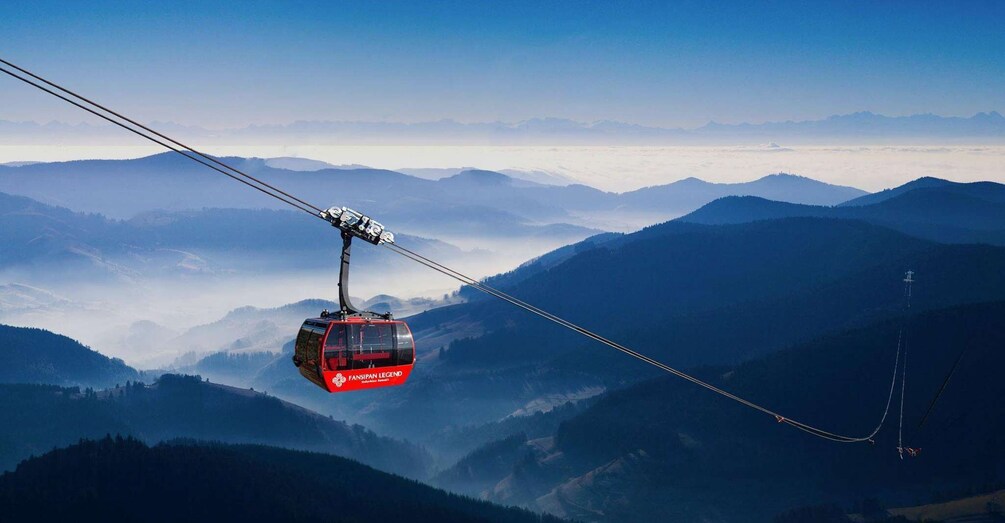 A red cable car suspended over a mountainous landscape. 1