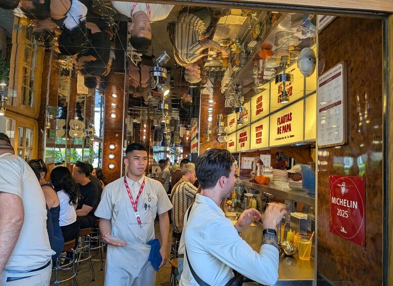 A busy restaurant interior with hanging decorations and a sign for Michelin 2025. 1