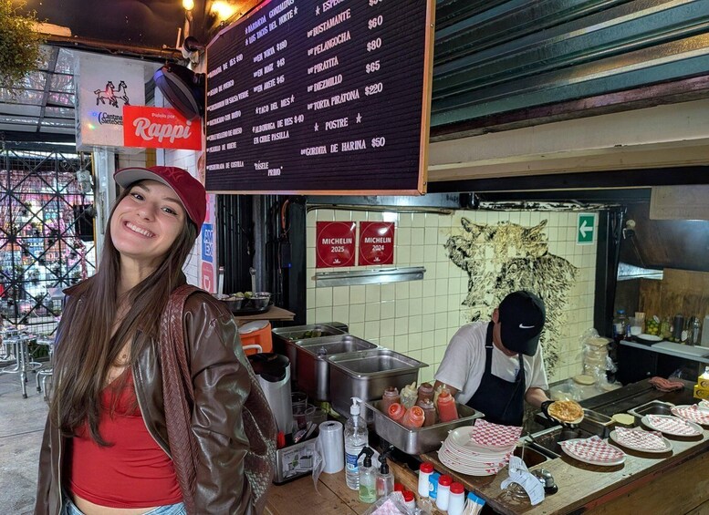A street food vendor preparing food, a menu board, and a person standing in front of the vendor. 3