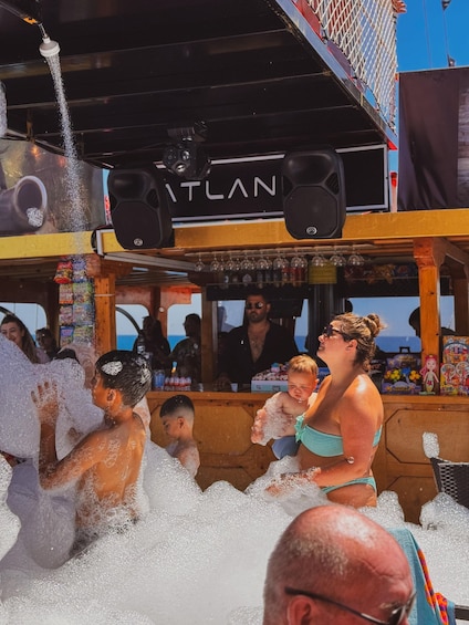 People playing in water on a boat with a bar and a sign that reads 'ITLAN'. 3