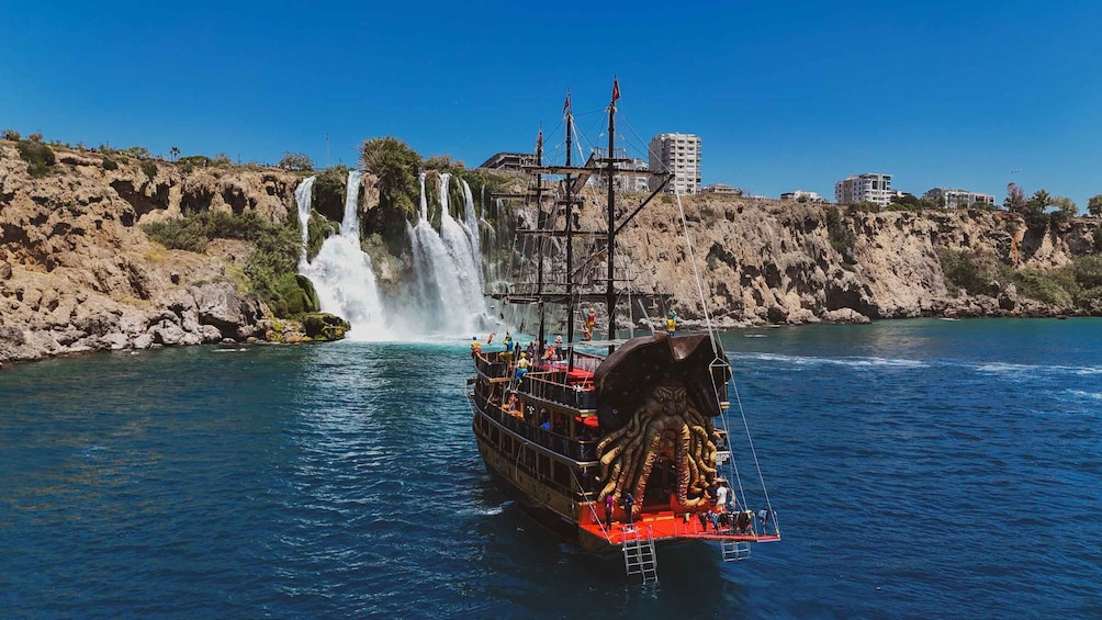 A ship with a large figurehead sailing near a waterfall. 2