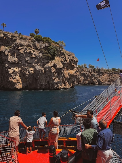 A group of people on a boat near rocky cliffs with clear blue water. 4