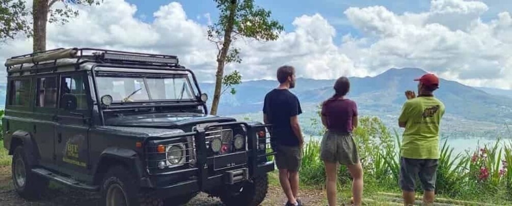 A black off-road vehicle parked on a grassy hill with a mountainous landscape in the background. 1
