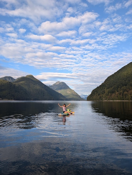 A person on a paddleboard in a calm lake surrounded by mountains. 4