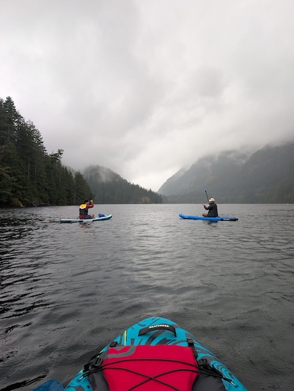 Two kayakers on a calm lake with misty mountains in the background. 3