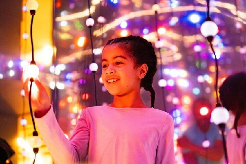 A person holding a light bulb in a festive setting with colorful lights. 2