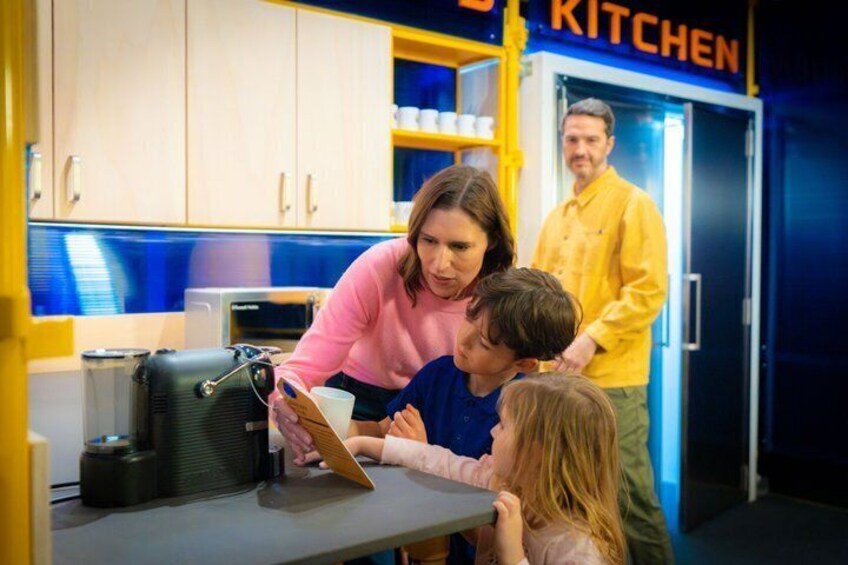 A family in a kitchen area with a refrigerator and cabinets. 4