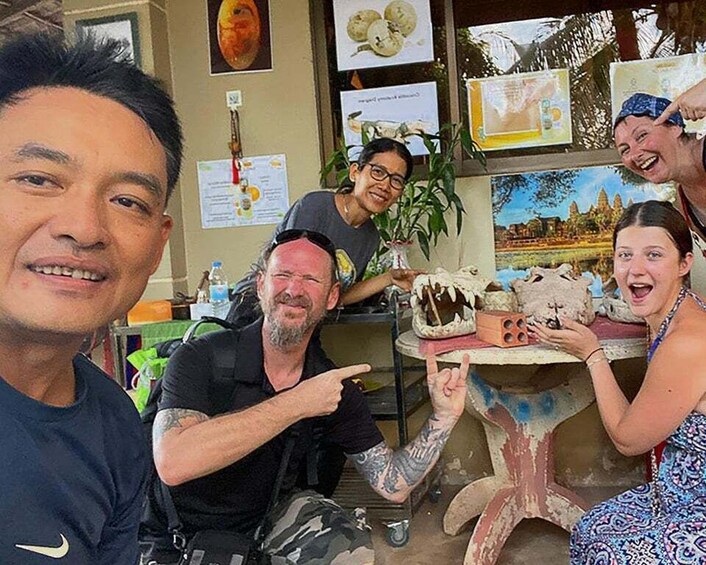 A group of people in a workshop with pottery and a painting of a temple. 3