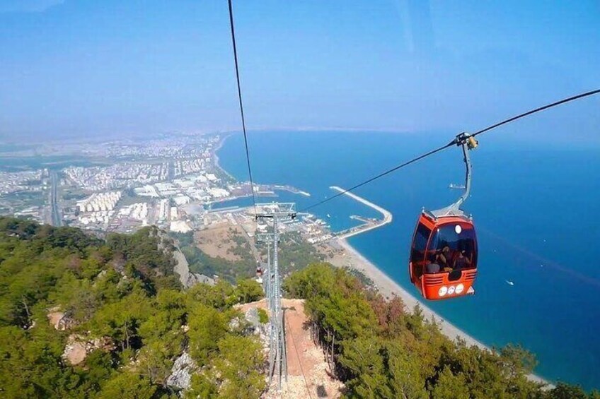 A cable car over a coastal city with a clear view of the sea and a bridge in the distance. 4