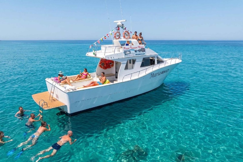 A white boat named 'Maria4Bani' with people swimming and lounging on its deck. 2
