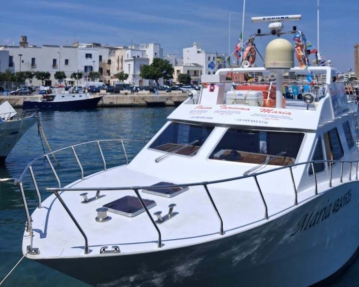 A white boat docked at a marina with buildings and other boats in the background. 5