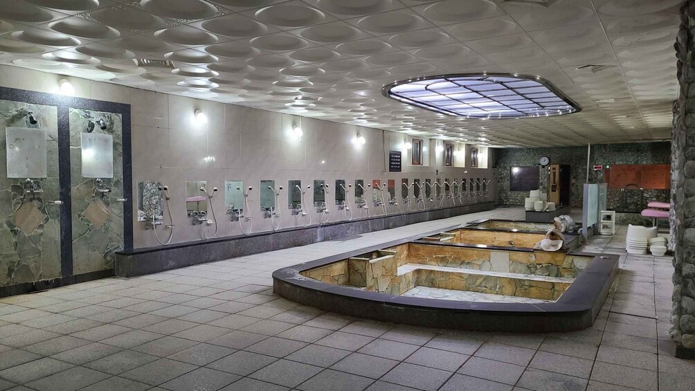 A public restroom with multiple sinks and a central seating area. 5