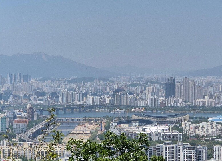 A cityscape with high-rise buildings, a river, and mountains in the background. 2