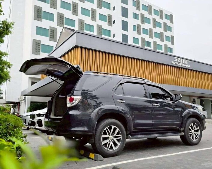 A dark-colored SUV parked in front of a building with a sign that reads 'sann hotel.' 4