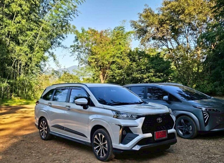 Two Toyota SUVs parked on a dirt path surrounded by dense greenery. 2
