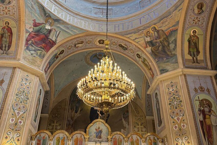 A grand chandelier in a church with ornate ceilings and religious artwork. 5