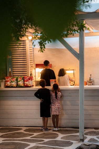 A family at a food kiosk with snacks and drinks visible. 2