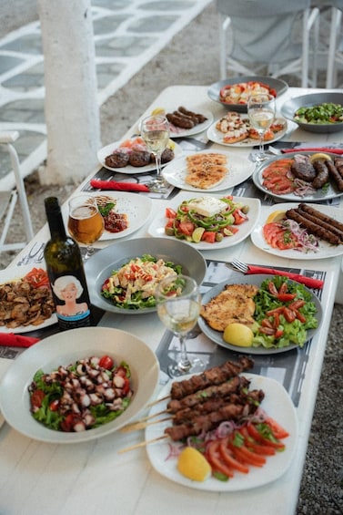 A variety of dishes and drinks on an outdoor table, including salads, grilled meats, and a bottle of wine. 4
