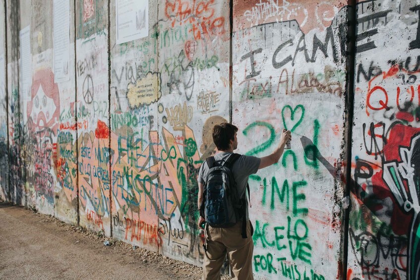 A person drawing on a wall covered with graffiti. 2