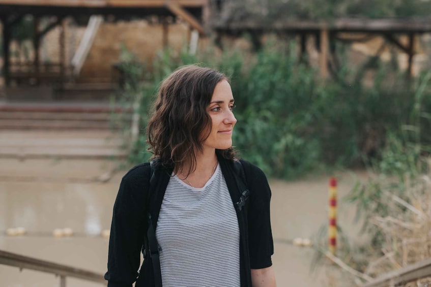 A person standing outdoors with a building and vegetation in the background. 5