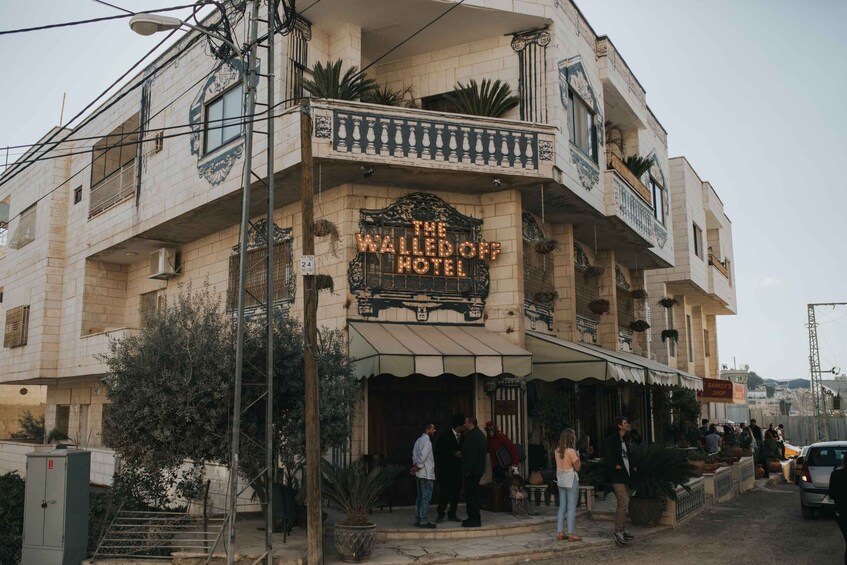 A building with a sign reading 'The Walled Off Hotel' and a visible entrance. 4