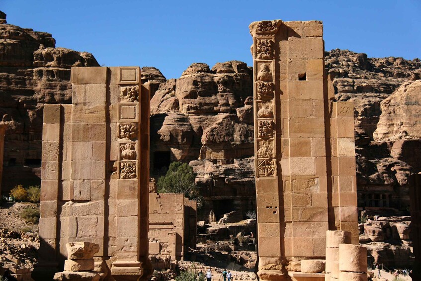 Ancient stone columns with carvings, set against a rocky backdrop. 2