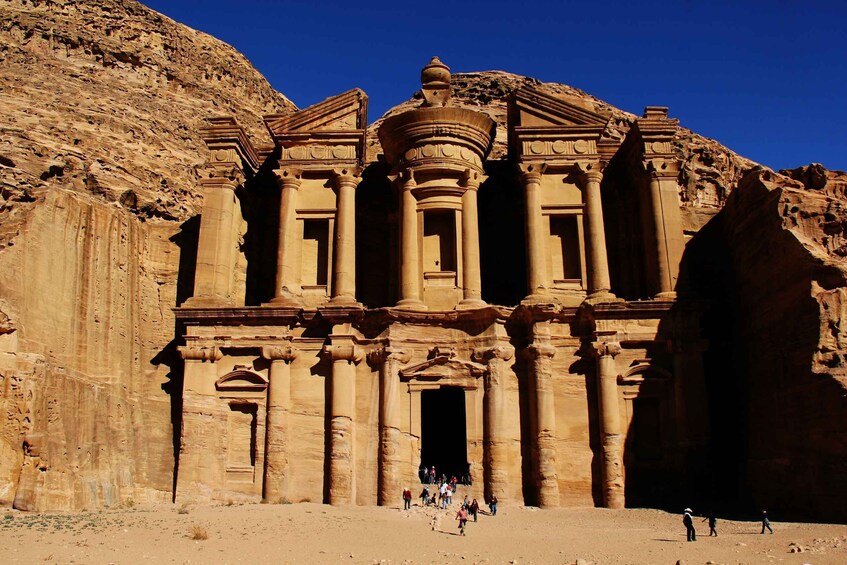 A large sandstone structure with columns and a central dome, surrounded by rocky terrain. 3